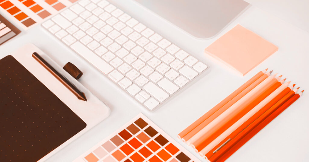 Mesa de trabajo en primer plano en la que aparecen diferentes elementos relacionados con el diseño gráfico y el branding